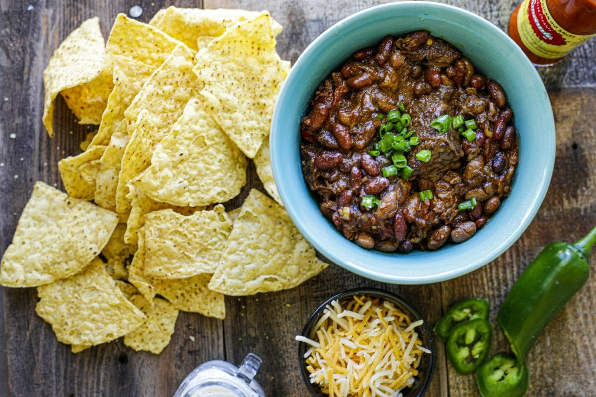 Des nachos nature, un bol de chili con carne, du fromage râpé et un piment Jalapeno tranché