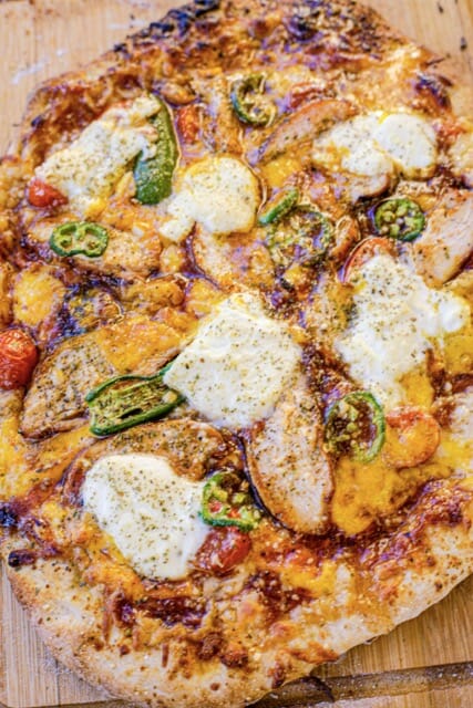 Gros plan de haut sur une pizza avec du poulet, de la mozzarelle, des piments et de la sauce BBQ