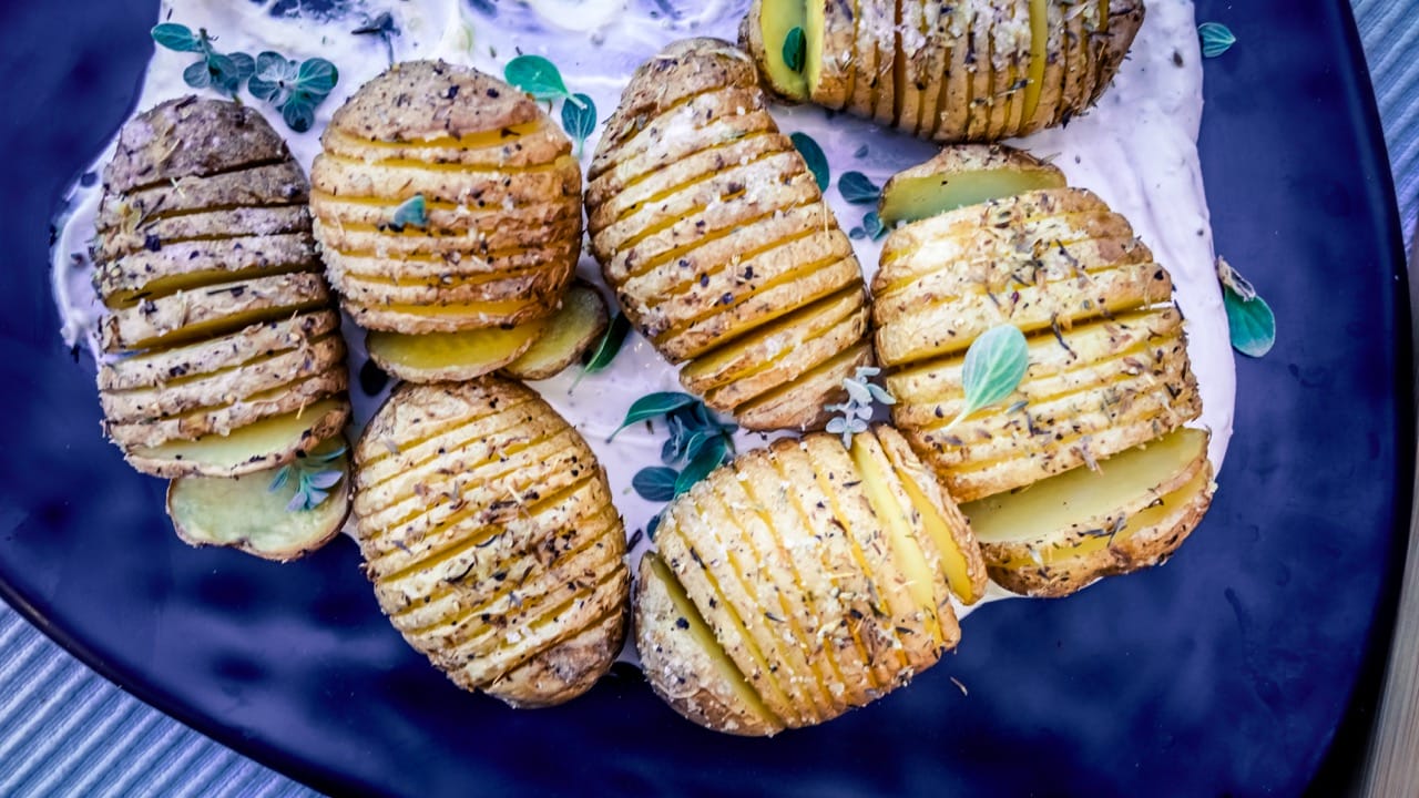 Pommes de terre Hasselback, sauce aux oignons vue de haut dans une assiette noire