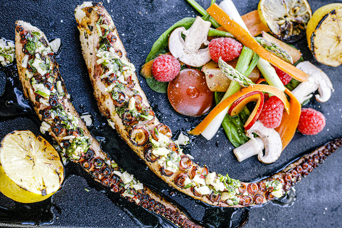 2 tentacules de poulpe grillées; une salade de légumes variées avec des framboises et 1/2 citron grillé.
