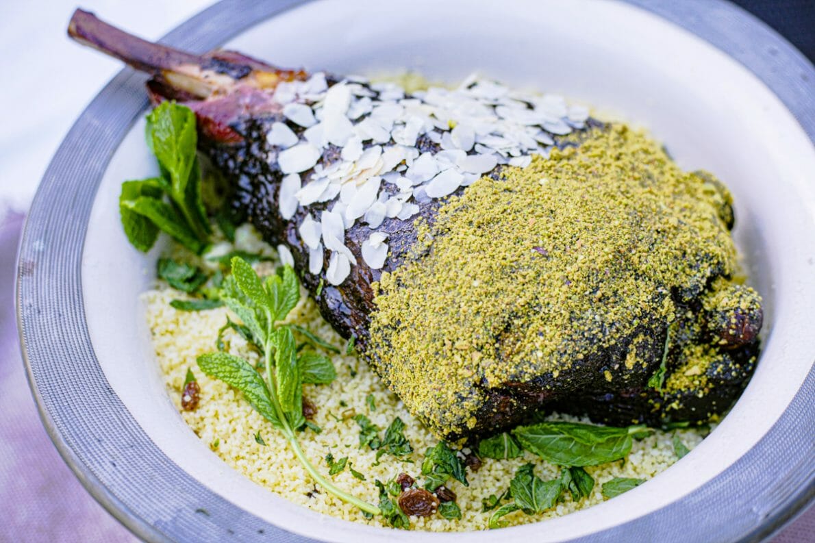 Un gros gigot d'agneau sur de la semoule, avec des amandes effilées et de la poudre de pistaches.