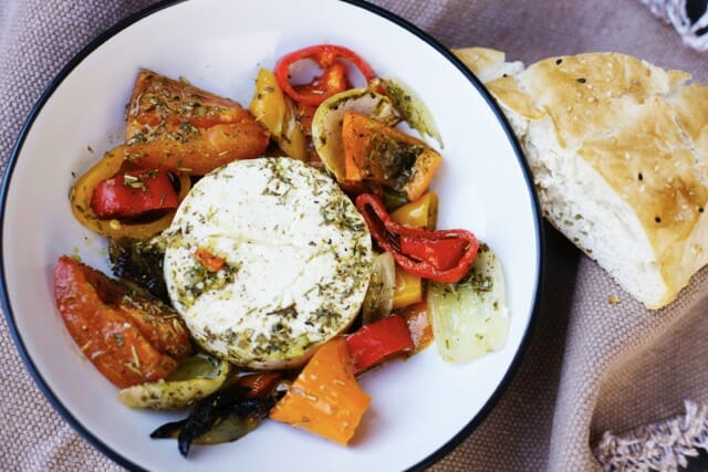 Un morceau de Feta grillée entourée de légumes grillés aussi, un morceau de pain sur le côté.