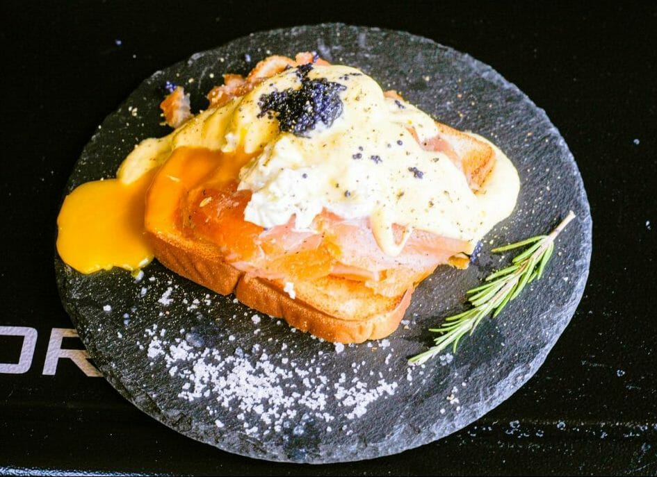 Un toast au saumon fumé avec un oeuf poché, une sauce hollandaise et du caviar dessus.
